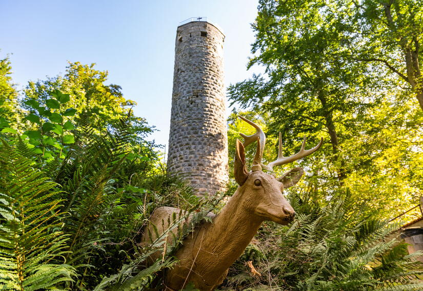 Wallenburger Turm mit einer Reh-Holzskulptur im Vordergrund