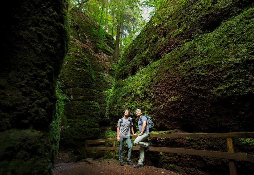 Zwei Wanderer zwischen hohen Felswänden in der Drachenschlucht bei Eisenach