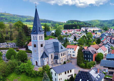 Blick auf die Kirche in Brotterode aus der Vogelperspektive, links im Hintergrund der Inselsberg