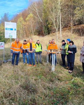 Landrätin Peggy Greiser, der beauftragten Baufirma Wolf und eine Reihe anderer Interessierter beim Baggerbiss durch Bürgermeister Kay Goßmann.