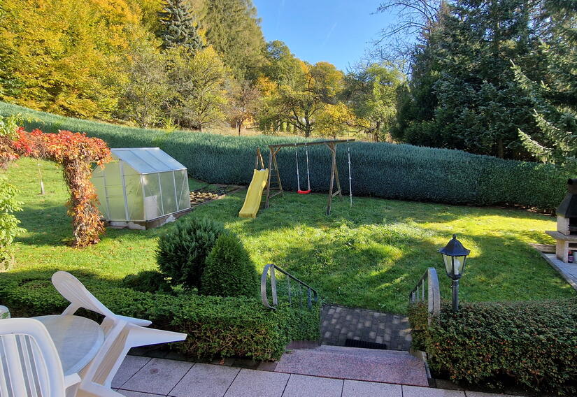 Blick von der Terrasse in den Garten mit Schaukel, Rutsche und Kamin