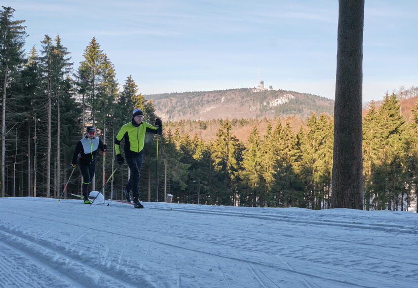 Zwei Skifahrer unterwegs auf der Kalte-Heide-Loipe in Brotterode, im Hintergrund ist der Inselsberg zu sehen